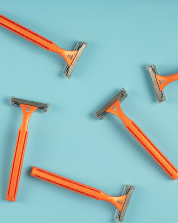 Plastic razor on blue background. The concept of using a razor. Razor device. The concept of skin care. Epilation hair removal. Orange men's shaving razors, top view.の写真素材