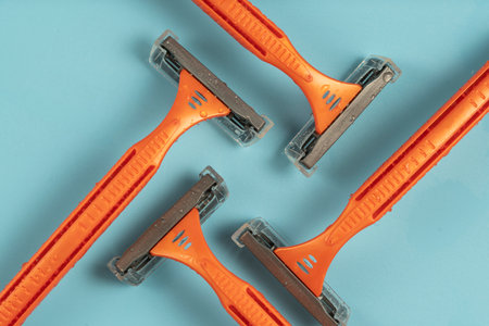 Plastic razor on blue background. The concept of using a razor. Razor device. The concept of skin care. Epilation hair removal. Orange men's shaving razors, top view.の写真素材