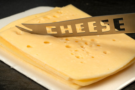 Knife with the inscription Cheese. Texture of Radomer cheese with close-up on a black background