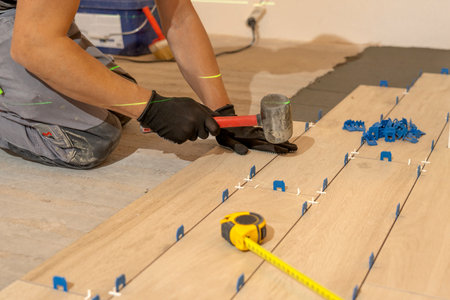 Repair and construction. Laying ceramic tiles using cement on the floor close-up. A man lays slabs on the floor and walls.の写真素材