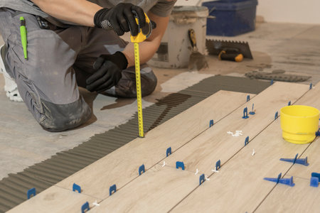 Repair and construction. Laying ceramic tiles using cement on the floor close-up. A man lays slabs...