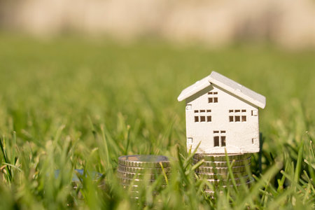 Stacks of coins on the lawn with house house, saving money to buy a house, financial plan mortgage loan concept.の写真素材