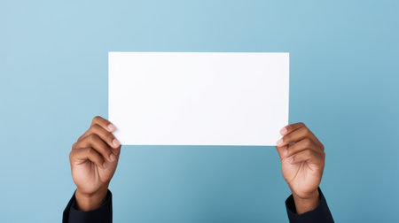 Hands holding blank paper sheet on blue background, mockup for design Generative AIの素材