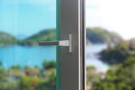 Sliding door of a balcony. Close-up of the lock on the door with and nice landscape of background. White PVC door and double security glass.の写真素材