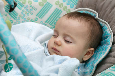 Baby sleeping in a rocking chair covered with a blanket.の写真素材