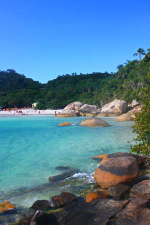 JOAQUINA BEACH, FLORIANOPOLIS, SANTA CATARINA, BRAZIL - MARCH 22, 2009: A surfer on the rocks looking at the sea and waiting for the right time to jump into the water. Behind the joaquina beach.のeditorial素材