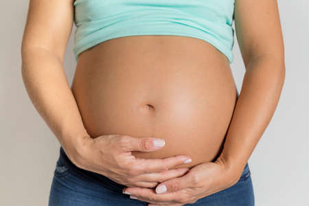 Pregnancy. Pregnant woman caressing and showing her tummy.