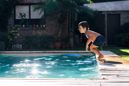 Little boy jumping in a pool. Child get fun in the swimming pool of his home. Outdoors activities in...
