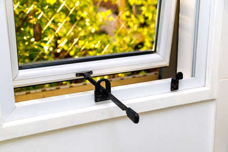 Aluminum outward opening top-hung window of a kitchen. Frame of white color. View from interior.