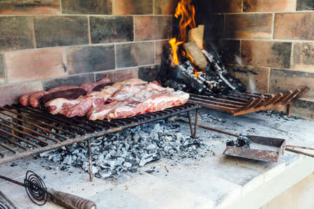 The meat of a traditional Argentine barbecue being roasted on a grill located in the patio of a house. Weekend tradition in Argentina.の写真素材
