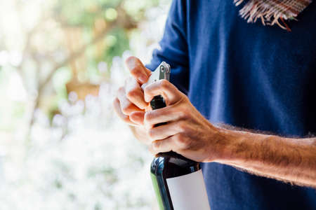 A young man opening a bottle of red wine with a corkscrew. Asado day in Argentina.の写真素材