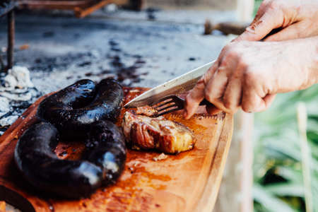Argentine man cutting roast beef. Traditional asado from Argentina. Barbecue.の写真素材