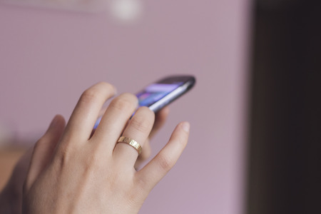 Woman's hand scrolling on a smartphone screenの写真素材