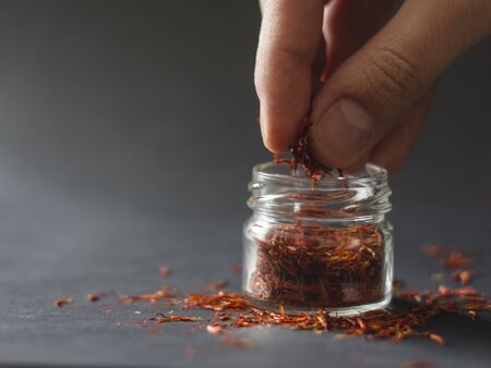 Hand picking saffron from a small jarの写真素材