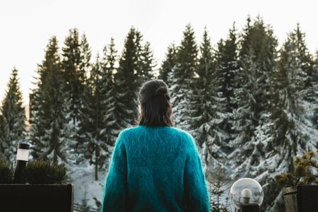Young woman looking towards a forest from a balcony