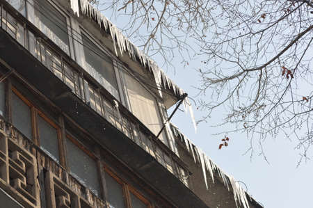 Beautiful icicles hang from the roof. Winter beauty in the city. Frozen water. Icicles on the...