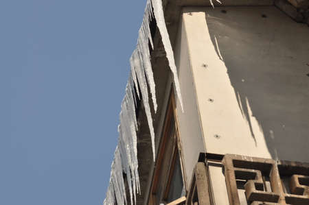 Beautiful icicles hang from the roof. Winter beauty in the city. Frozen water. Icicles on the...