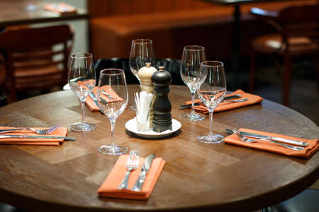 wooden table served with plates, forks, spoons, glasses, napkins in the restaurantの写真素材