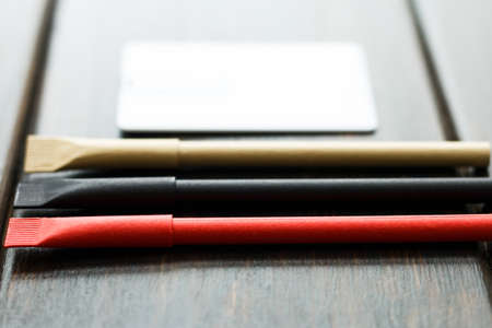 business usb flash card card and black, red, beige pens. Office desk wooden dark background top view...
