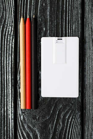 business usb flash card card and black, red, beige pens. Office desk wooden dark background top view...
