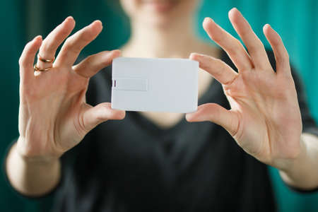 yong beautifull woman holding white bussines card or usb flash memory card mock upの写真素材