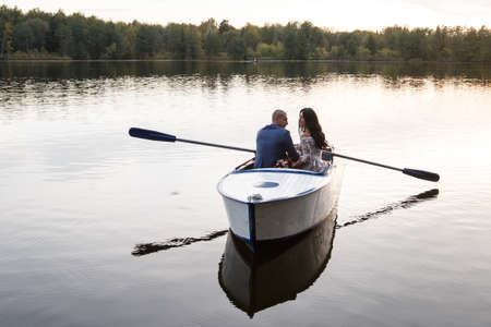 young beautiful couple honeymooners on a boat on a lake at sunset. wedding photosessionの写真素材