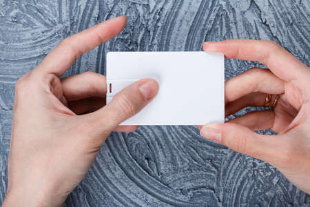 Hand holding blank white credit card mockup front side view. Plastic bank-card design mock up