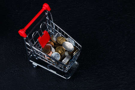 Coins in miniature of trolley isolated on black dark background.