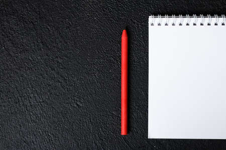 Top view of closed black cover notebook with pencil on black desk backgroundの写真素材