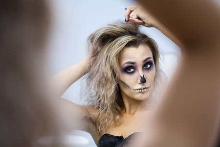 portrait of a blonde female flies spit on yourself, make hairstyle. Beautiful young european woman sitting near mirror and preparing herselfの写真素材