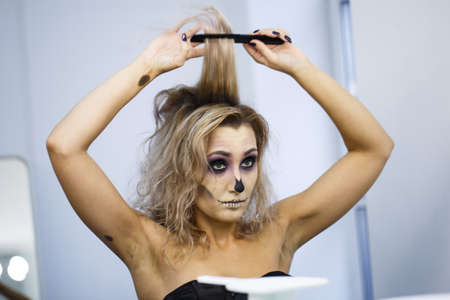 portrait of a blonde female flies spit on yourself, make hairstyle. Beautiful young european woman sitting near mirror and preparing herselfの写真素材