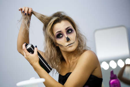 portrait of a blonde female flies spit on yourself, make hairstyle. Beautiful young european woman sitting near mirror and preparing herselfの写真素材