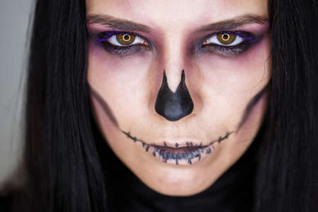 Halloween. Portrait of young beautiful girl with make-up skeleton on her face.Close up portrait of a girl in a high fashion, beauty styleの写真素材
