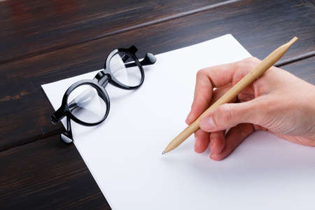 Closeup image of hand writing down on a blank. mockup Top view of female hands making some notes  work, studying, shopping, blogging concept. Mock up, copy space for your text.の写真素材