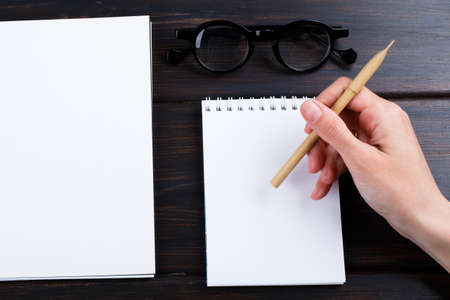 Closeup image of hand writing down on a blank. mockup Top view of female hands making some notes  work, studying, shopping, blogging concept. Mock up, copy space for your text.の写真素材