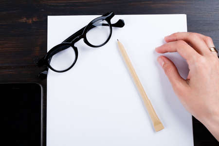 Closeup image of hand writing down on a blank. mockup Top view of female hands making some notes  work, studying, shopping, blogging concept. Mock up, copy space for your text.の写真素材