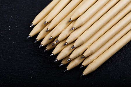 Detail of some of the beige pen pencil tips is evident, seen on a black background.の写真素材