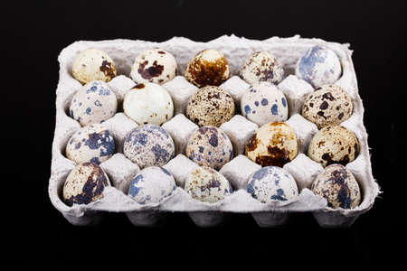 Overhead view of fresh quail eggs in wooden box over purple background Top view with copy space....