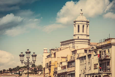 View of Girona Cathedral with its colorful river houses in a great sunny day with vinatge colours, digitally edited. Costa Brava.の写真素材