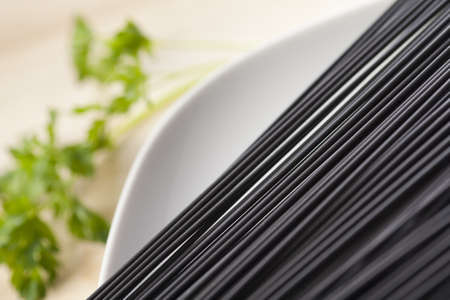 Dish of raw sepia spaghetti with parsley out of focus.の写真素材