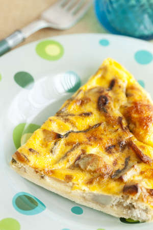 Portion of a delicious asparagus and artichoke  homemade quiche on a white dish.の写真素材