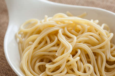 Cooked Spaghetti in a big white spoon.の写真素材