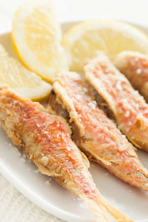 Fried red mullet fish with salt and lemon, ready to eat.