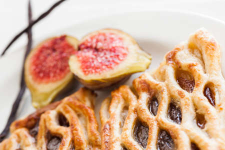 Homemade fig lattice pastry with fresh figs, two pieces of vanilla and one dought in the background.の写真素材