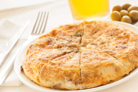 Spanish potato omelet called "Tortilla de Patatas" with beer and olives, ready to eat.の写真素材