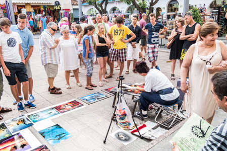 TOSSA DE MAR, SPAIN - 21 JULY  Tourists look a street artist painter in the street in Tossa de Mar, small touristic village of Costa Brava,   Tossa de Mar July 21, 2013 のeditorial素材