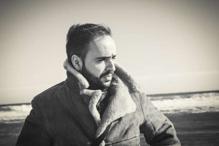 Serious man looking away in the beach in a sunny day.の写真素材