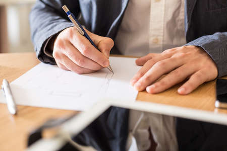 Architect working at his desk drawing a sketch.の写真素材