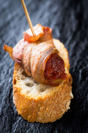 Typical spanish tapas: Delicious pork sausage called chistorra with bacon.の写真素材