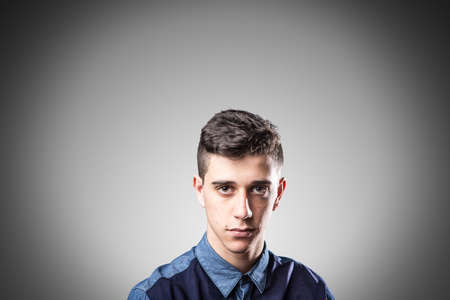 Serious boy looking at camera isolated on grey background.